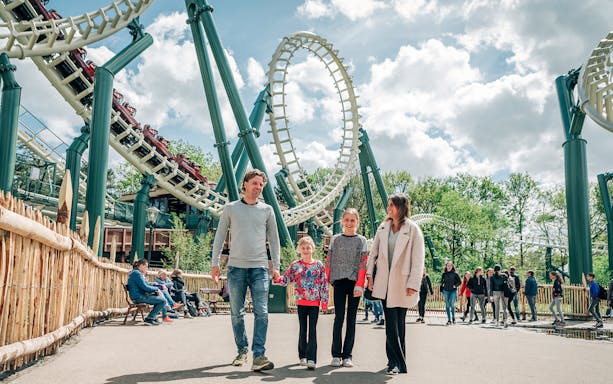 Family walking near roller coaster at Efteling theme park, Netherlands.