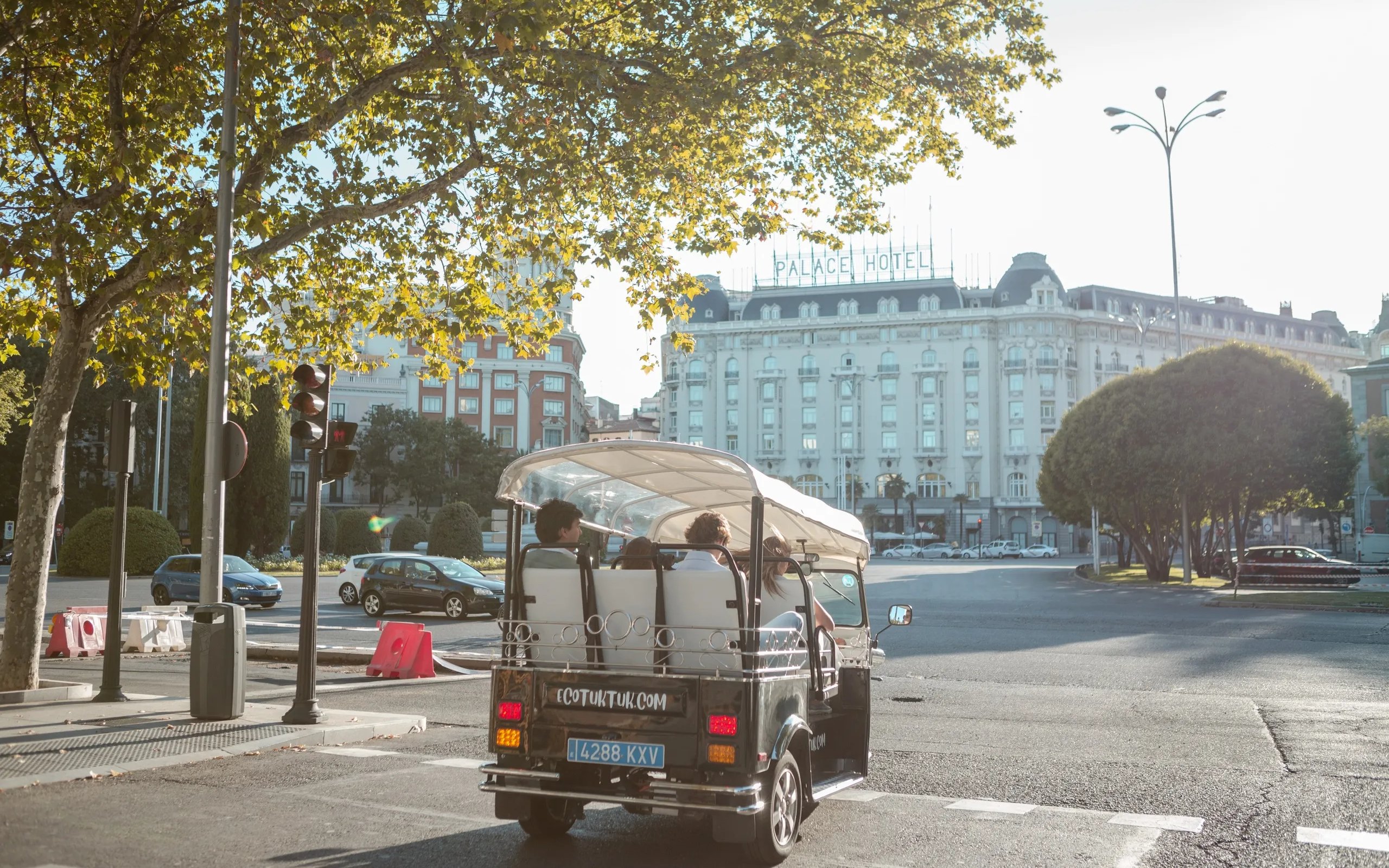 Tourists on an electric tuk-tuk tour near Palace Hotel in Madrid.