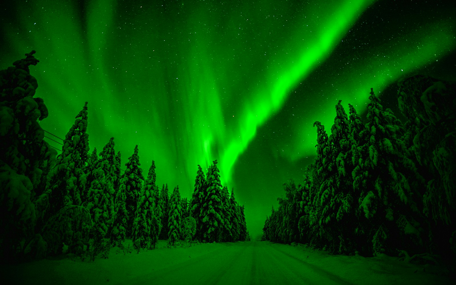 Snowmobiles on snowy path under Northern Lights in Rovaniemi, Finland.