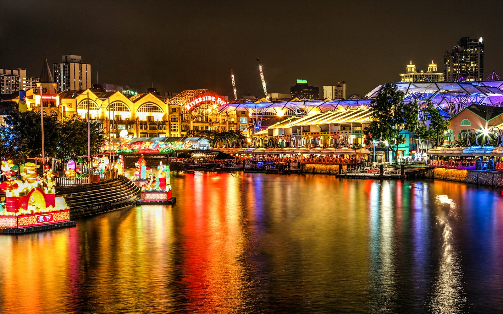 Singapore River Cruise at night with vibrant lights reflecting on water near Riverside Point.