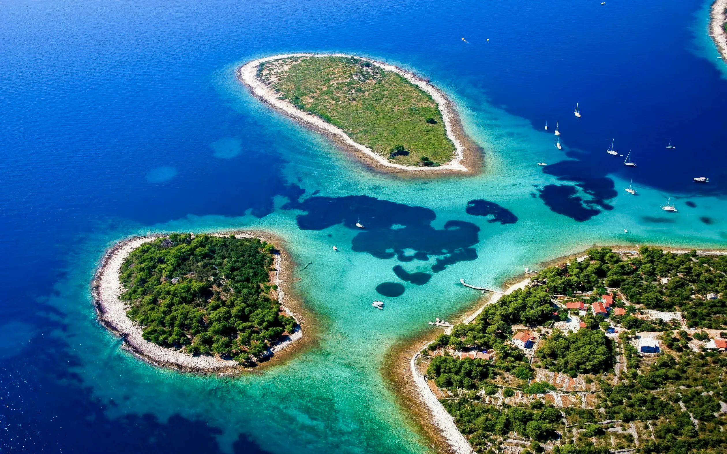 Aerial view of Blue Lagoon's turquoise waters and islands near Trogir, Croatia, with boats anchored nearby.