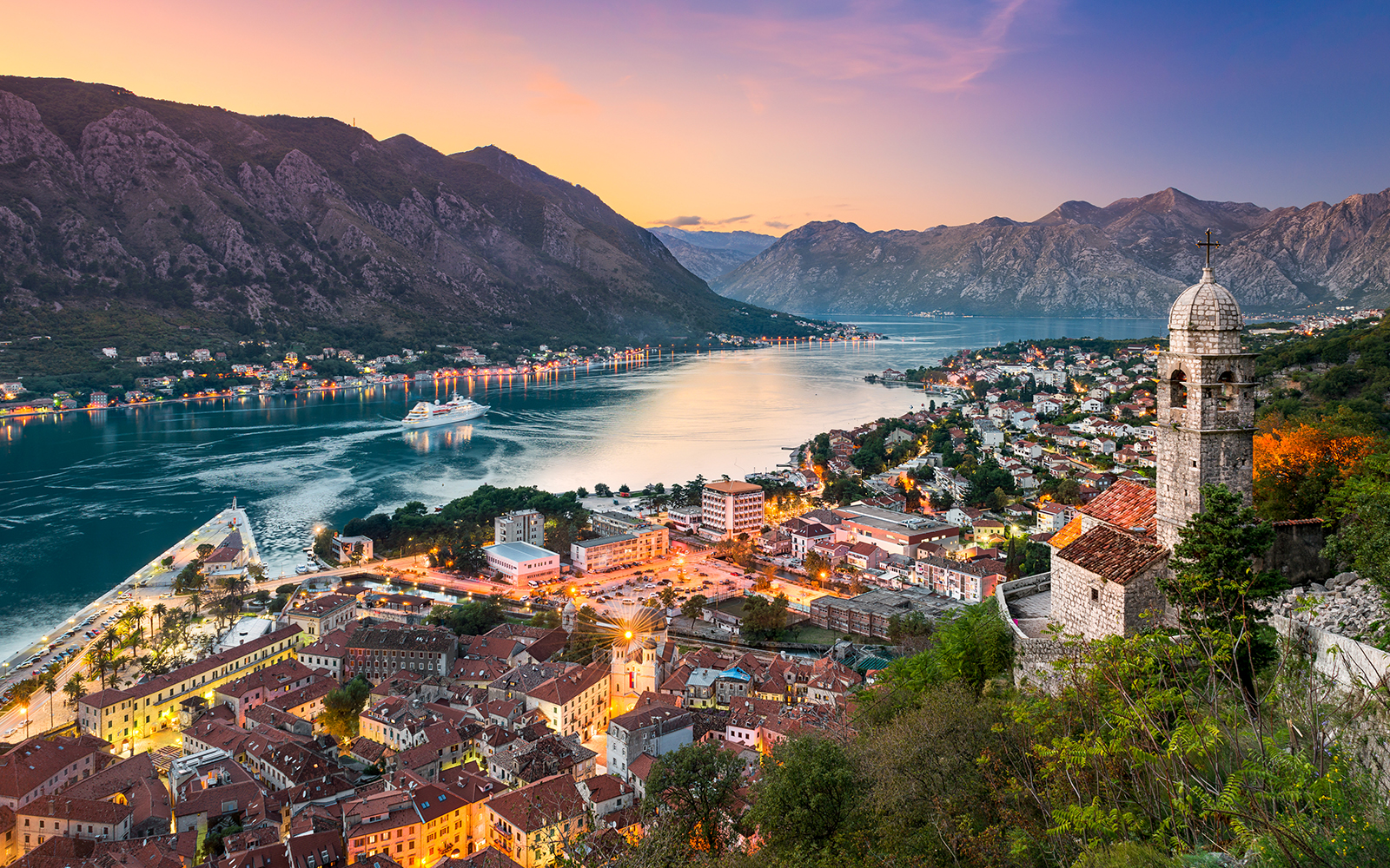 Kotor town in Montenegro with bay view and historic church at sunset.