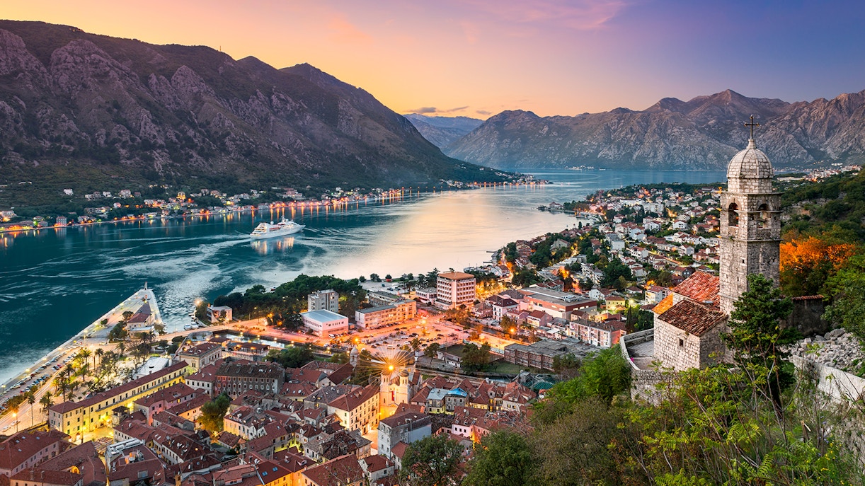 Kotor town in Montenegro with bay view and historic church at sunset.