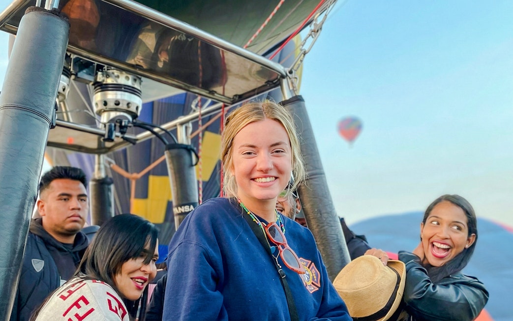 Hot air balloon passengers smiling during flight near Mexico City.