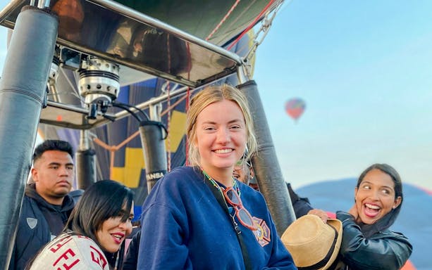 Hot air balloon passengers smiling during flight near Mexico City.