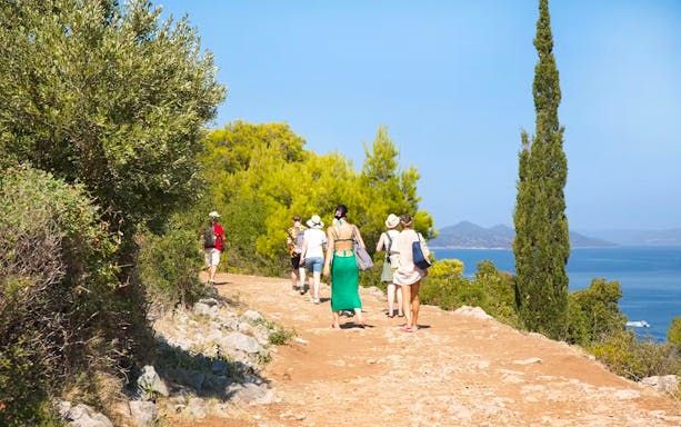 Guests walking on a scenic path with sea views on Elaphite Island during Karaka cruise tour.