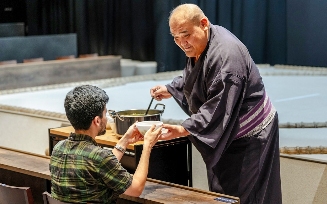 Sumo wrestler serving soup to a guest at The Sumo Hall Hirakuza Osaka.