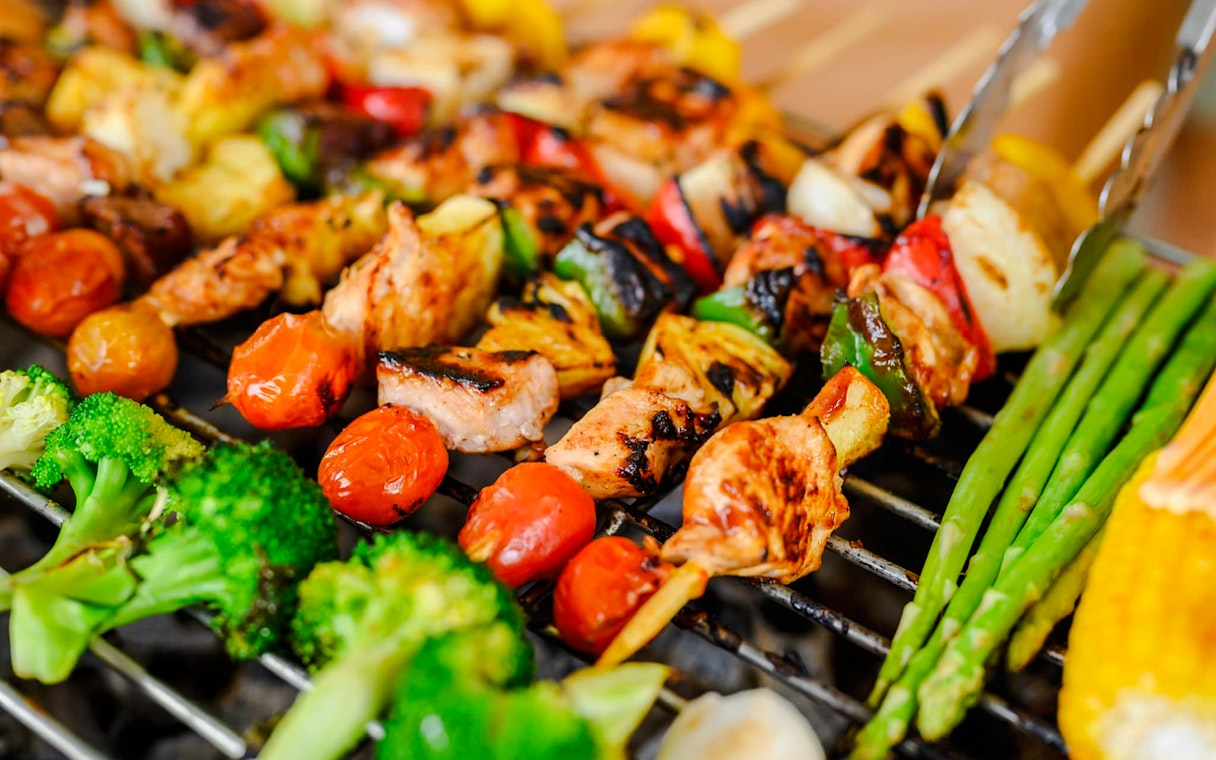 Grilled skewers with vegetables and meat at a beach barbeque.