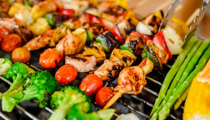 Grilled skewers with vegetables and meat at a beach barbeque.