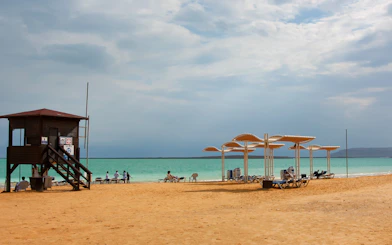 Dead Sea resort beach with lifeguard tower and sunshades by the water.