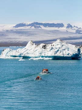Boats navigating Jökulsárlón Glacier Lagoon with icebergs in Iceland.