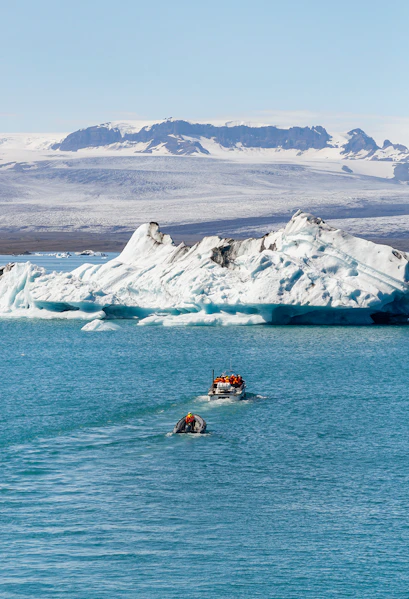 Boats navigating Jökulsárlón Glacier Lagoon with icebergs in Iceland.