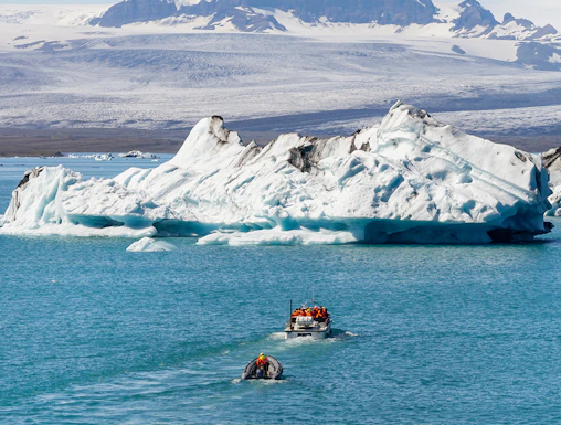 Boats navigating Jökulsárlón Glacier Lagoon with icebergs in Iceland.