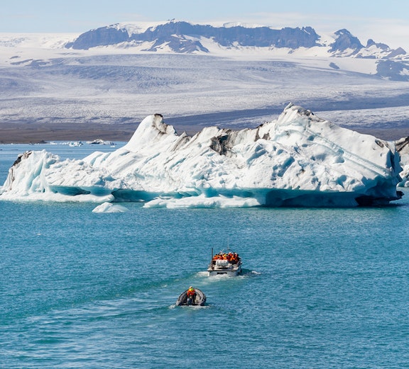 Boats navigating Jökulsárlón Glacier Lagoon with icebergs in Iceland.