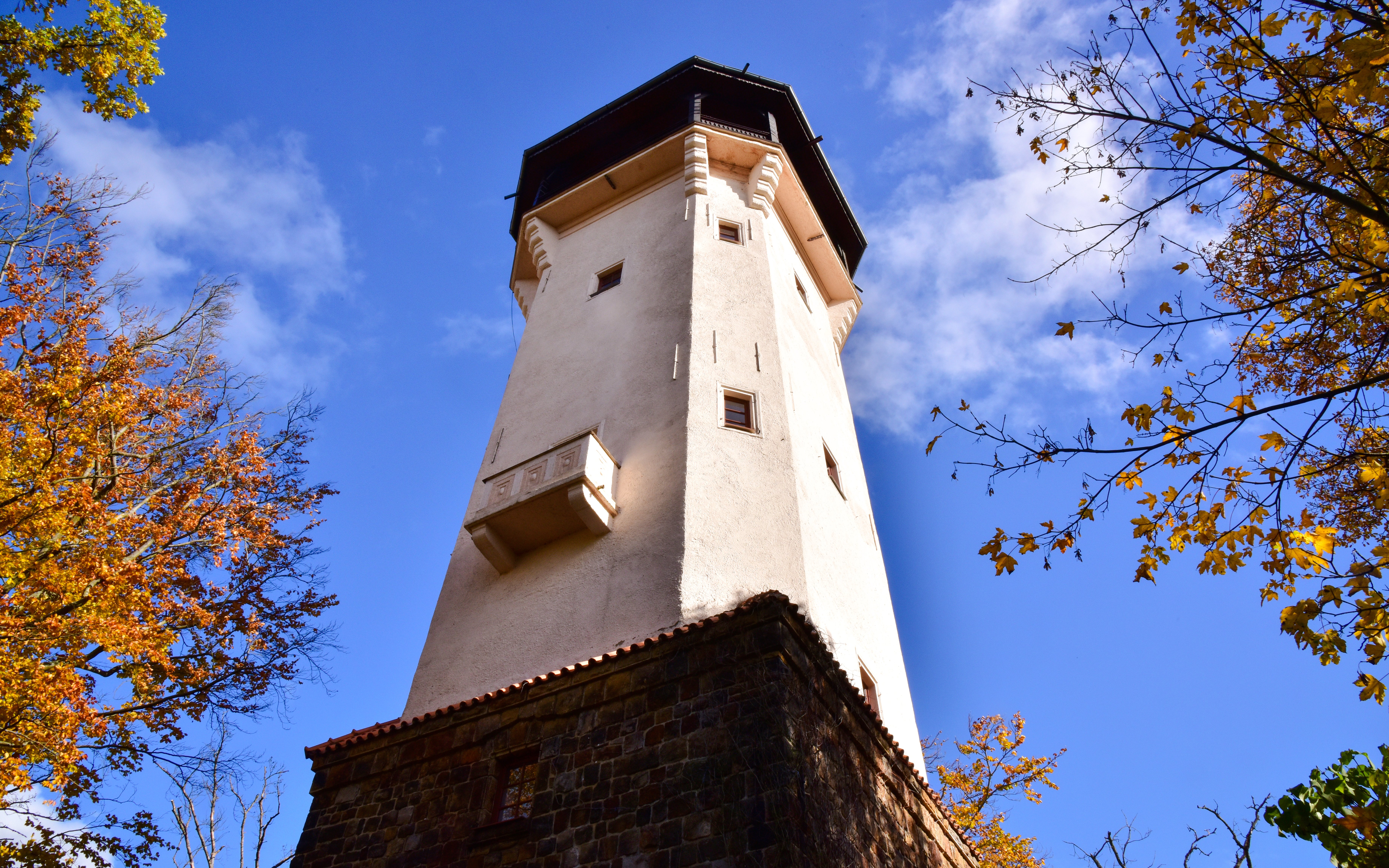 Diana observation tower in Karlovy Vary surrounded by autumn trees.