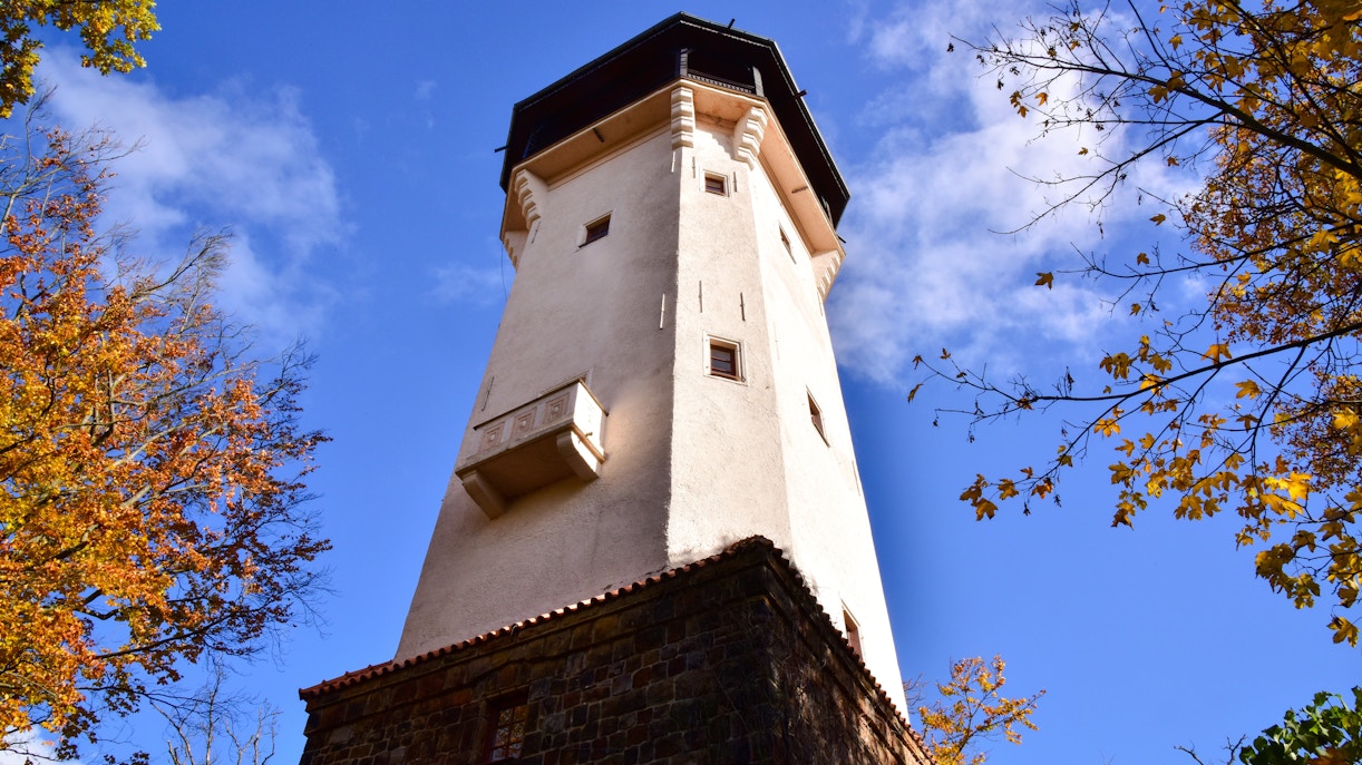Diana observation tower in Karlovy Vary surrounded by autumn trees.