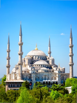 Blue Mosque with minarets in Istanbul, Turkey, surrounded by greenery.