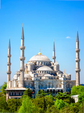 Blue Mosque with minarets in Istanbul, Turkey, surrounded by greenery.