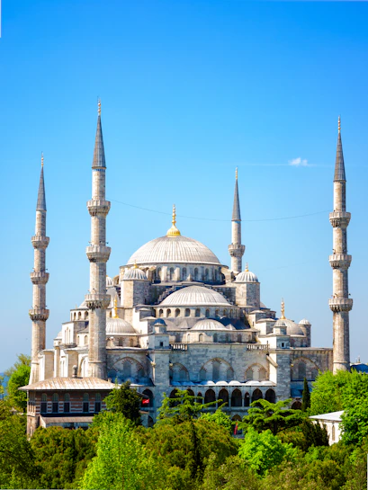 Blue Mosque with minarets in Istanbul, Turkey, surrounded by greenery.
