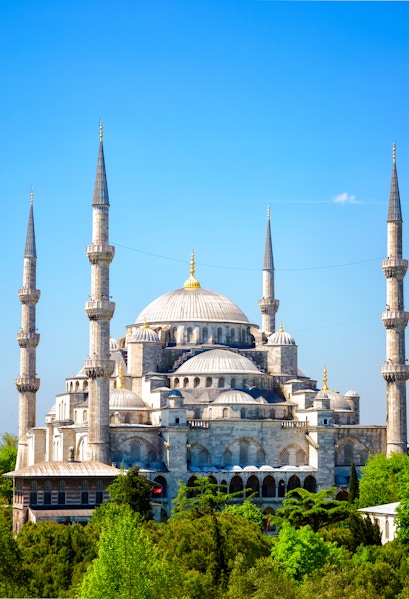 Blue Mosque with minarets in Istanbul, Turkey, surrounded by greenery.