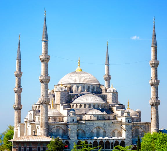 Blue Mosque with minarets in Istanbul, Turkey, surrounded by greenery.