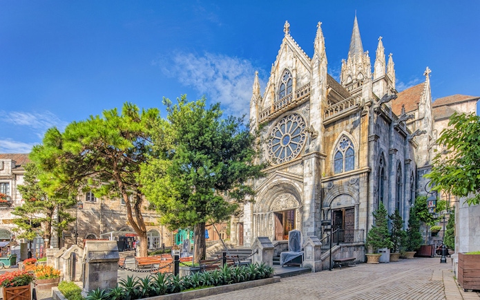 Gothic-style church facade in Bana Hills, Da Nang, Vietnam, surrounded by trees.
