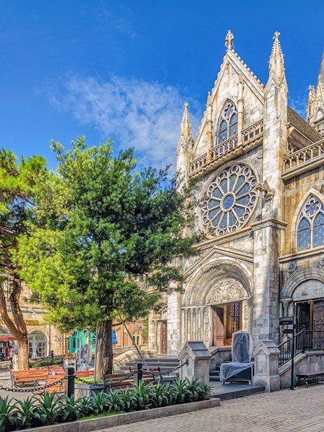 Gothic-style church facade in Bana Hills, Da Nang, Vietnam, surrounded by trees.