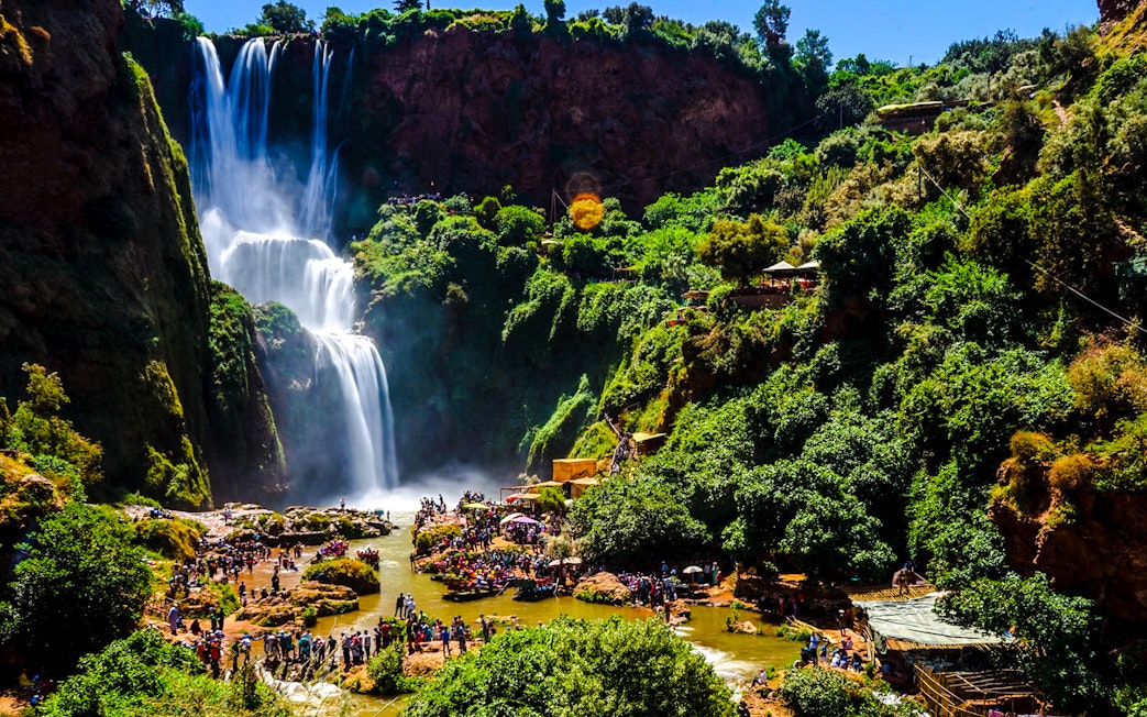 Ouzoud Waterfalls with tourists exploring the lush surroundings in Morocco.
