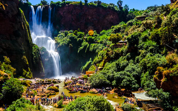 Ouzoud Waterfalls with tourists exploring the lush surroundings in Morocco.