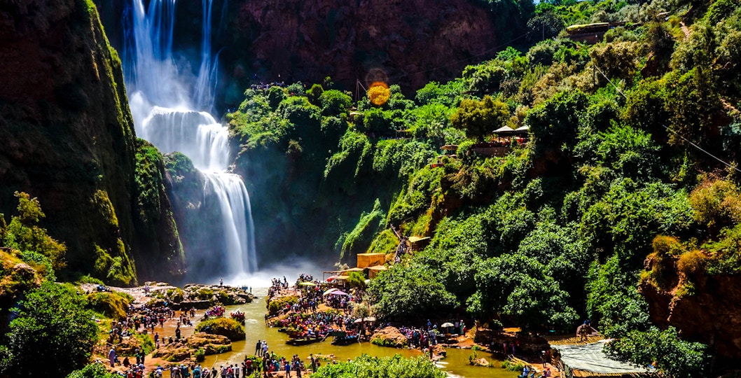 Ouzoud Waterfalls with tourists exploring the lush surroundings in Morocco.