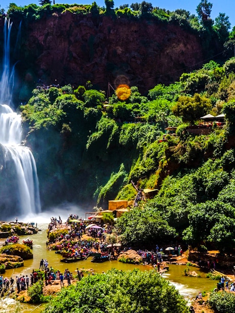 Ouzoud Waterfalls with tourists exploring the lush surroundings in Morocco.