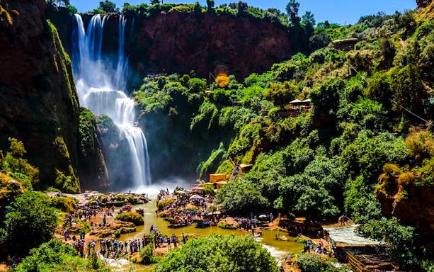 Ouzoud Waterfalls with tourists exploring the lush surroundings in Morocco.