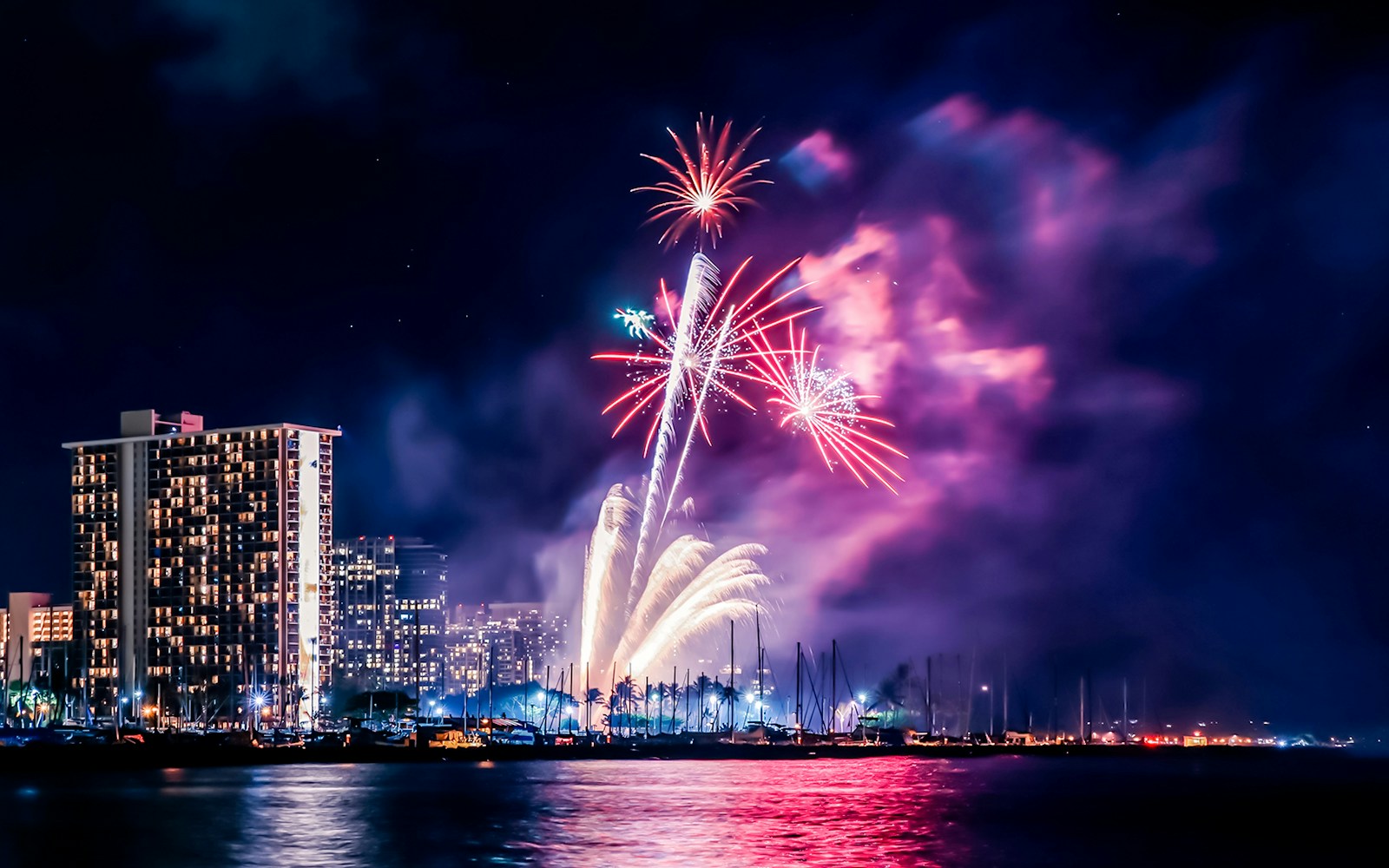 Fireworks display over Waikiki Beach, Honolulu, with city skyline and ocean in view, Oahu, Hawaii.