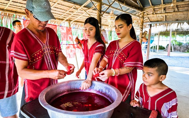 People in traditional attire participating in a dyeing activity at Kerchor Elephant Family, Phuket.