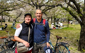 Couple with bikes under cherry blossoms at Osaka Castle park.