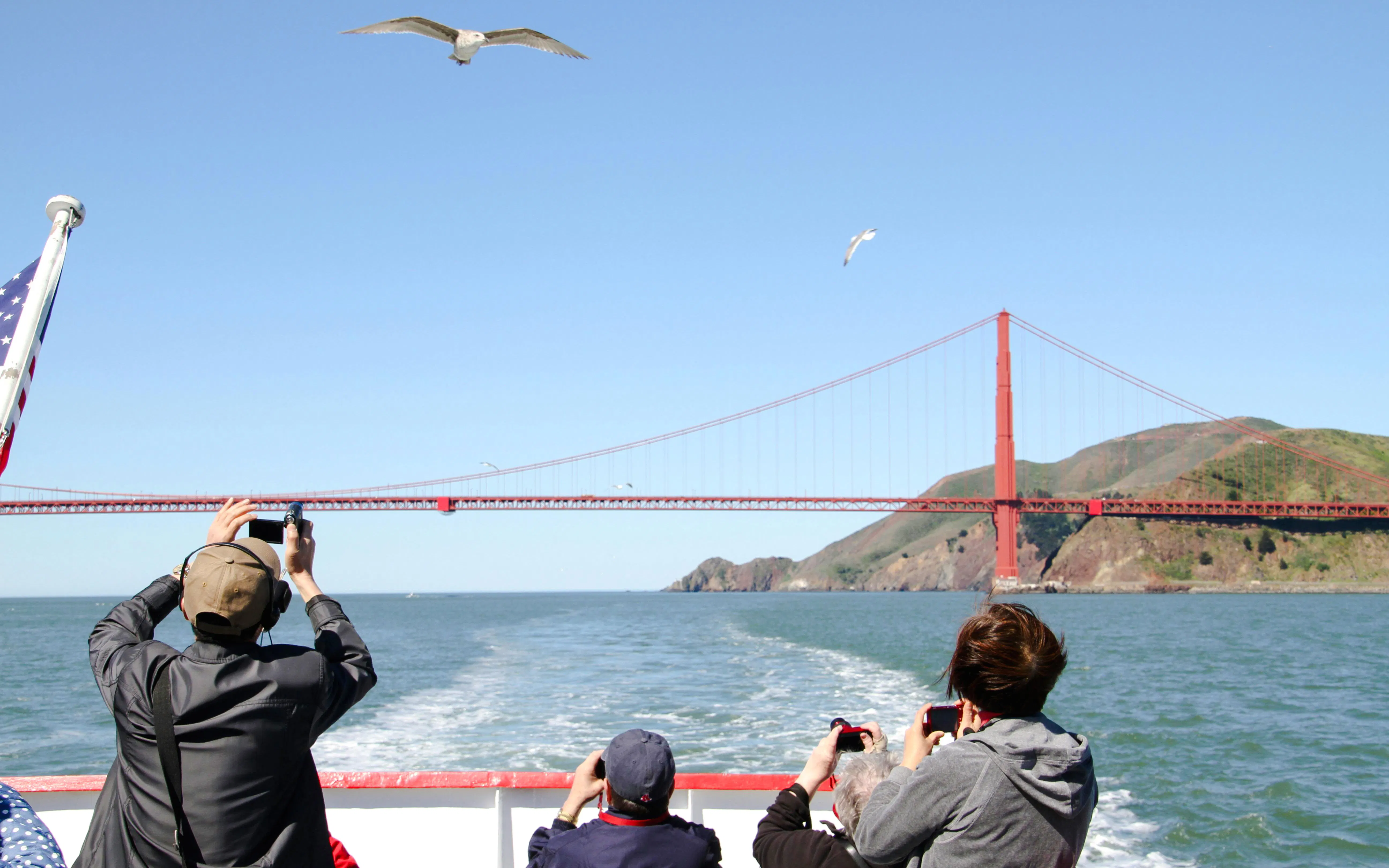 Cruise passengers photographing Golden Gate Bridge from boat in San Francisco Bay.