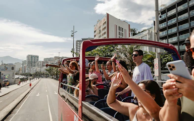 Tourists on an open-top bus enjoying Rio de Janeiro's cityscape during a hop-on hop-off tour.