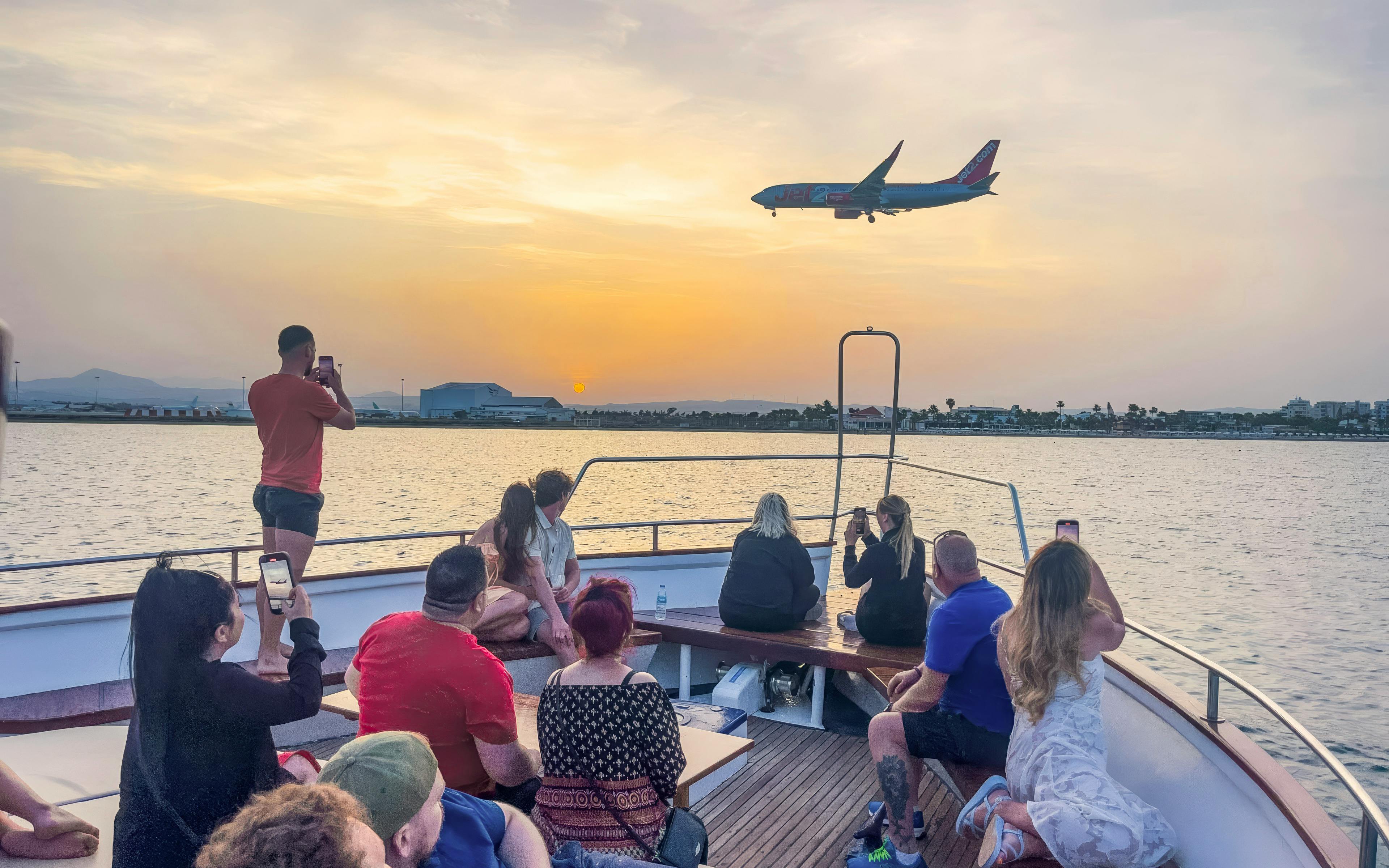 Sunset cruise from Larnaca with passengers watching a plane fly over the sea.