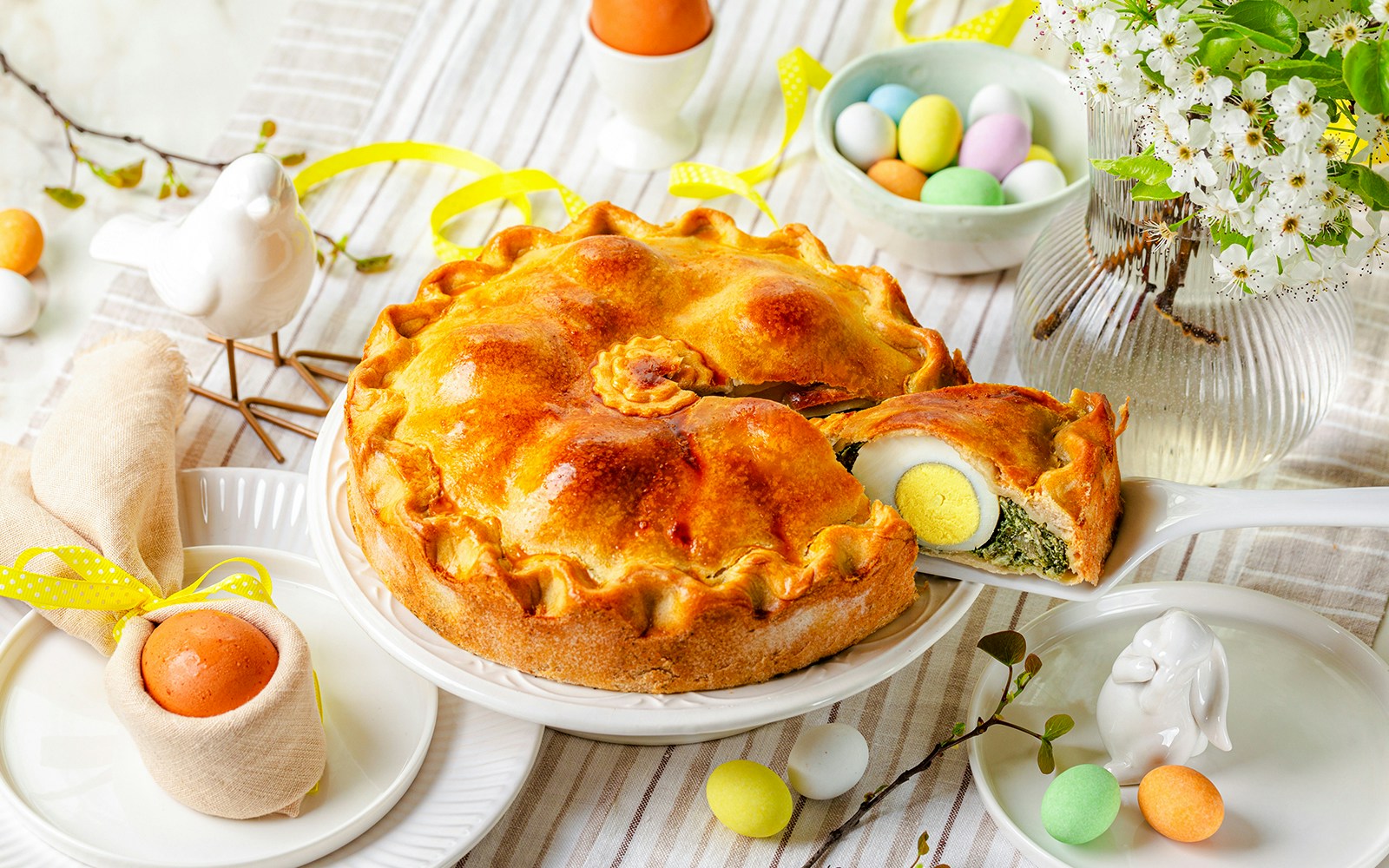 Easter table with Torta Pasqualina, a savory pie with spinach, silverbeet, leek, cheese, and whole boiled eggs, Italy.
