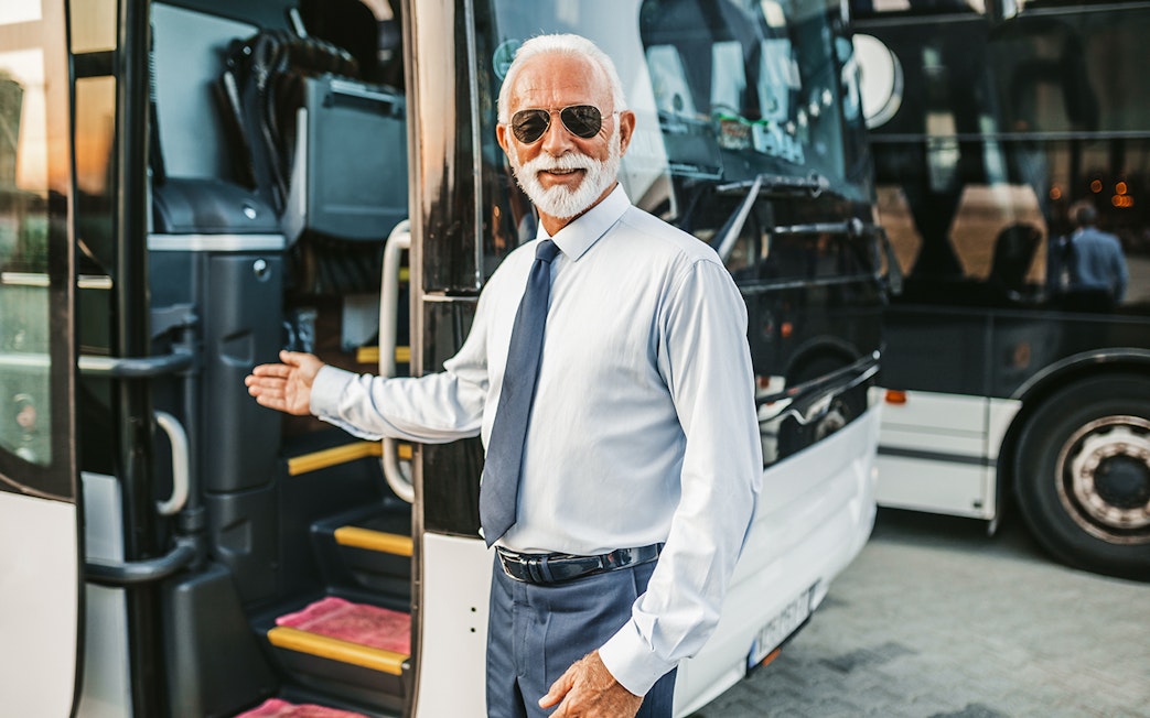 Bus driver welcoming passenger onto tour bus.