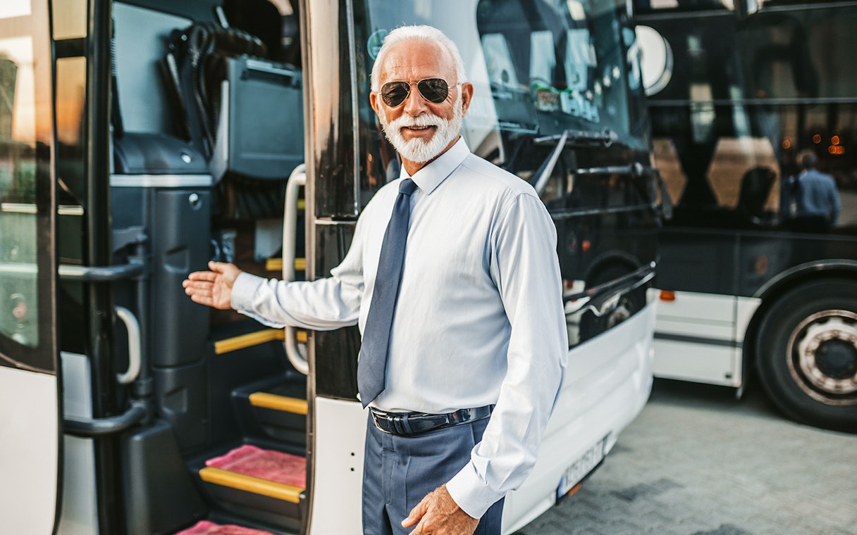Bus driver welcoming passenger onto tour bus.
