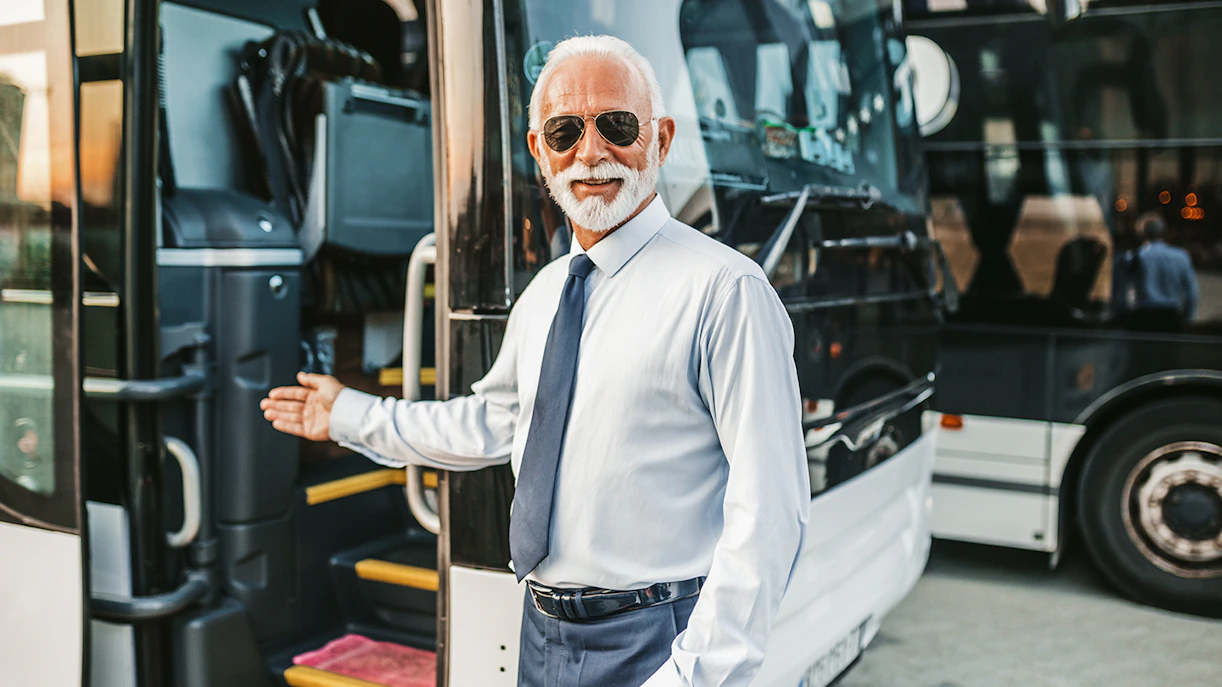 Bus driver welcoming passenger onto tour bus.