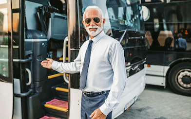 Bus driver welcoming passenger onto tour bus.