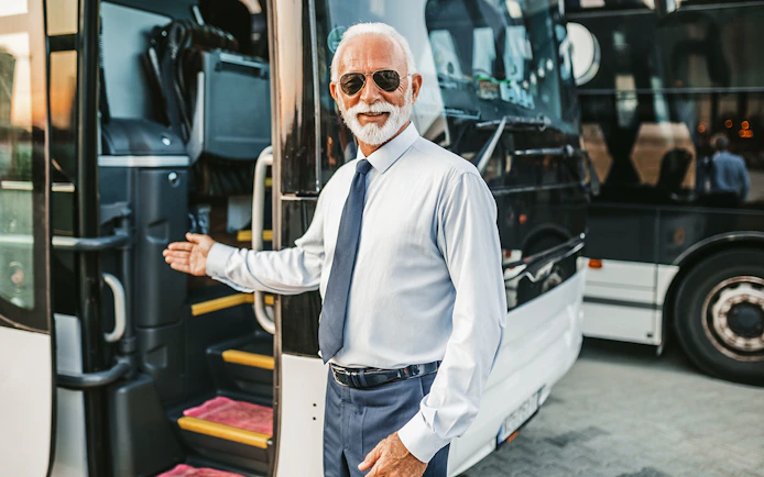 Bus driver welcoming passenger onto tour bus.