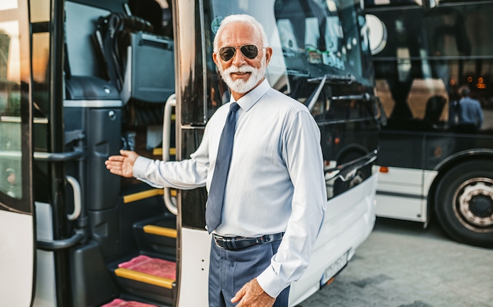 Bus driver welcoming passenger onto tour bus.
