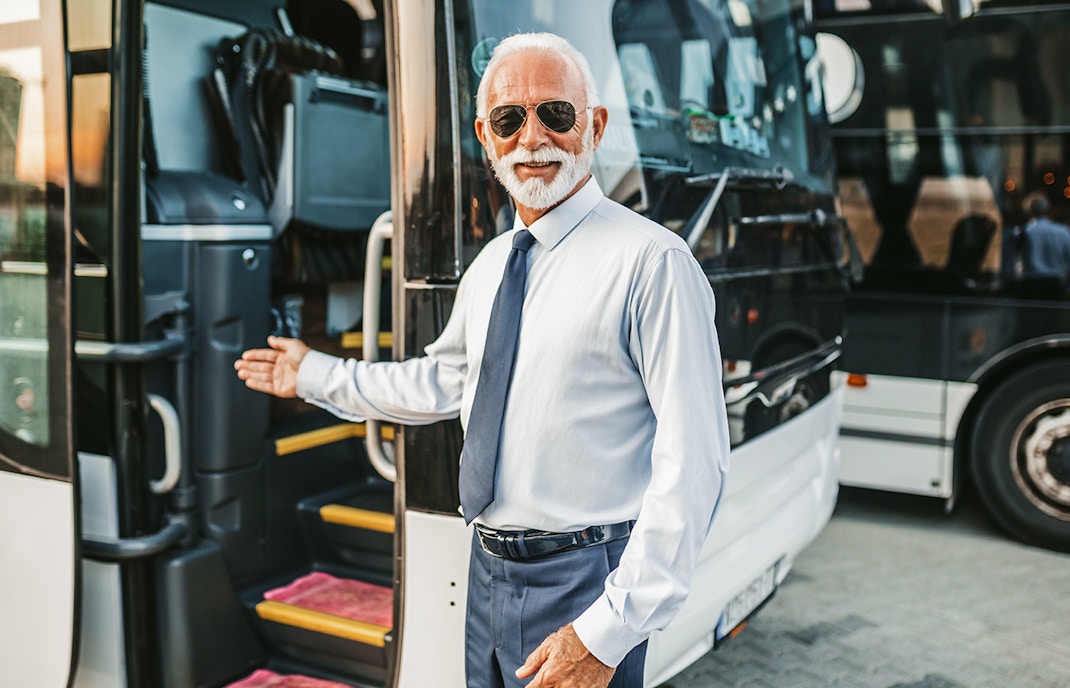 Bus driver welcoming passenger onto tour bus.