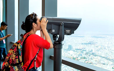 Visitor using telescope at Saigon Skydeck overlooking Ho Chi Minh City.