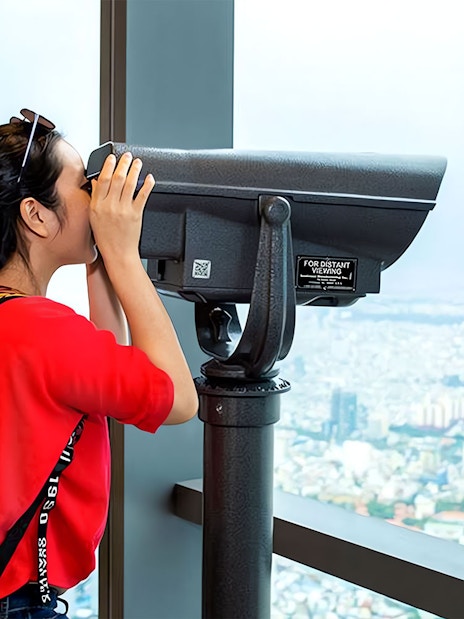 Visitor using telescope at Saigon Skydeck overlooking Ho Chi Minh City.