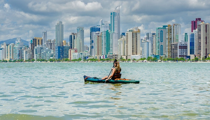 Kayaker paddling on Dubai Creek with city skyline in the background.