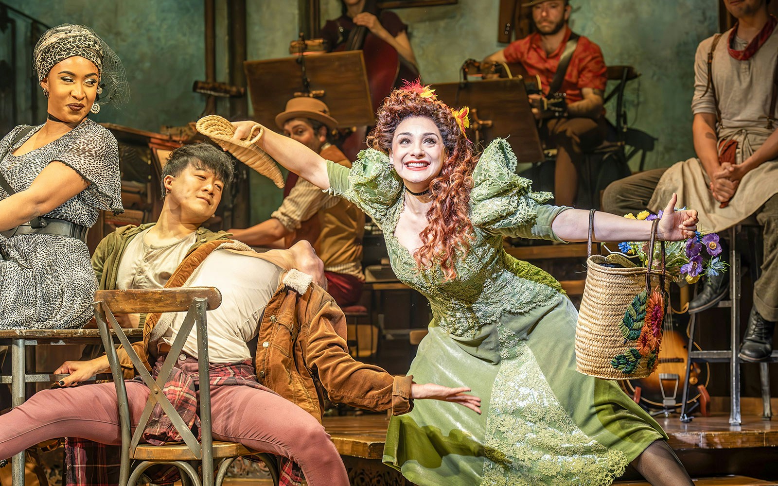 Performers in a theatrical scene, one in a green dress holding a basket, related to ghost stories.